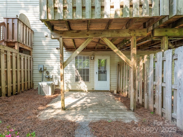 view of exterior entry featuring a patio, central air condition unit, and fence
