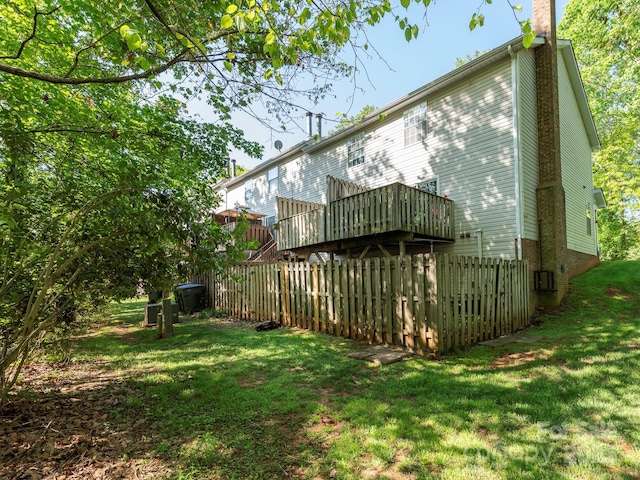 back of property featuring a deck, a yard, fence, and a chimney