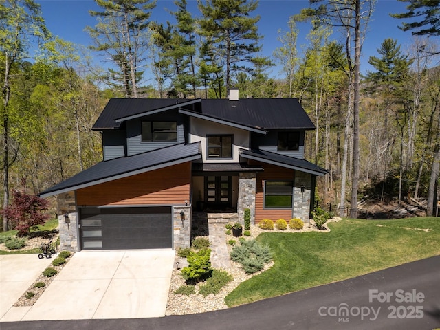 modern home with concrete driveway, stone siding, metal roof, a front yard, and an attached garage