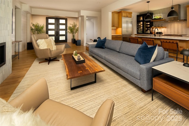 living room with indoor wet bar, french doors, and light wood-style flooring