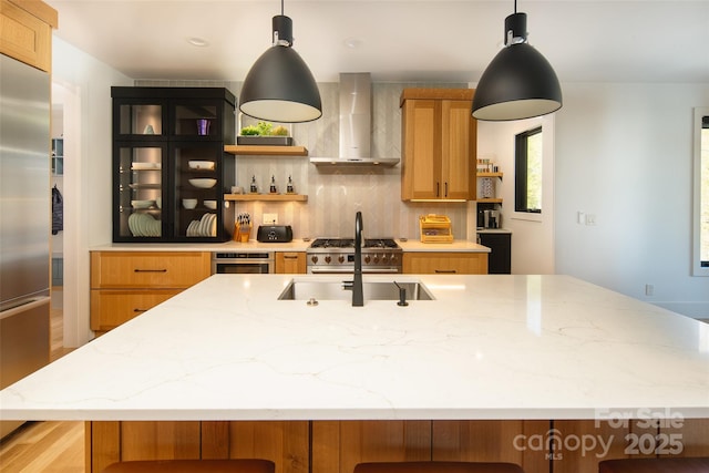 kitchen featuring stainless steel appliances, open shelves, backsplash, a sink, and wall chimney exhaust hood