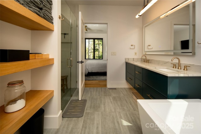 ensuite bathroom featuring baseboards, a shower stall, double vanity, and a sink