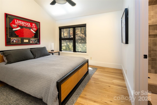 bedroom with a ceiling fan, vaulted ceiling, wood finished floors, and baseboards