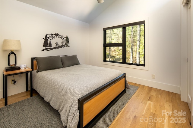 bedroom with lofted ceiling, light wood finished floors, and baseboards