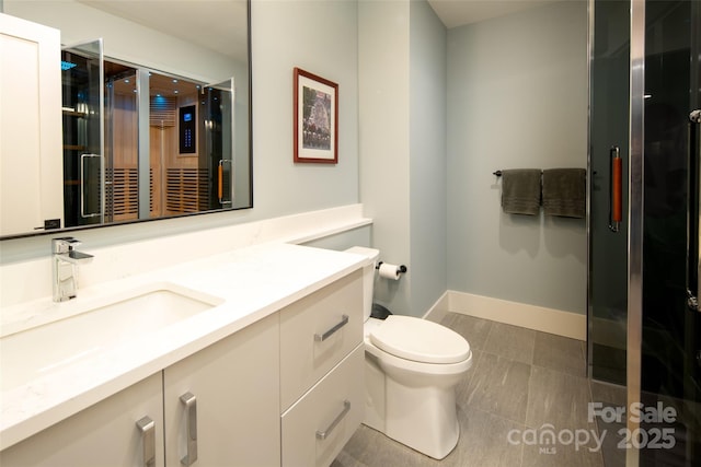 full bath featuring toilet, a shower stall, vanity, and baseboards