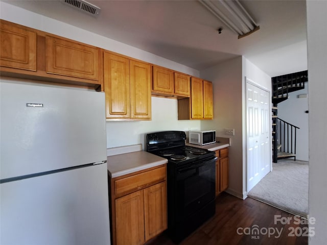 2527 Carya Pond Ln, Charlotte, NC 28212 - kitchen with dark wood-style flooring, black / electric stove, freestanding refrigerator, visible vents, and brown cabinets