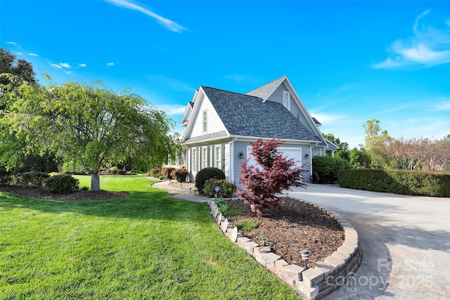 view of property exterior with an attached garage, roof with shingles, a yard, and concrete driveway