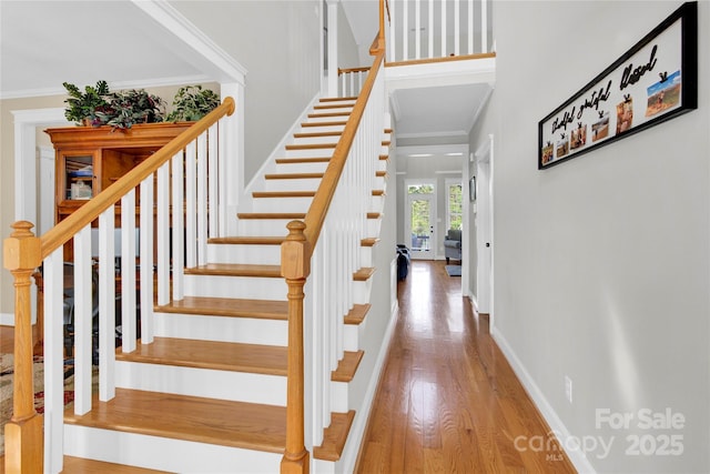 staircase featuring baseboards, crown molding, and wood finished floors