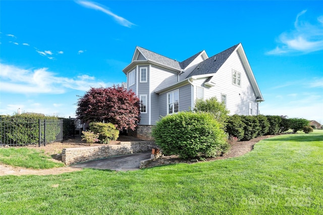 view of home's exterior with fence and a lawn
