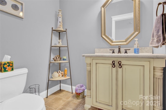 half bathroom featuring baseboards, vanity, tile patterned floors, and toilet