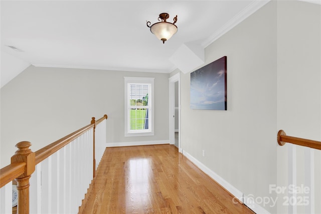 hallway with light wood-style flooring, baseboards, an upstairs landing, and ornamental molding