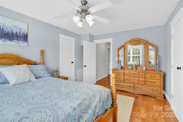 bedroom featuring baseboards, a ceiling fan, visible vents, and light wood-style flooring