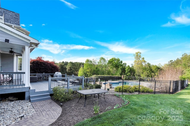 view of yard featuring a wooden deck, fence, a fenced in pool, and ceiling fan