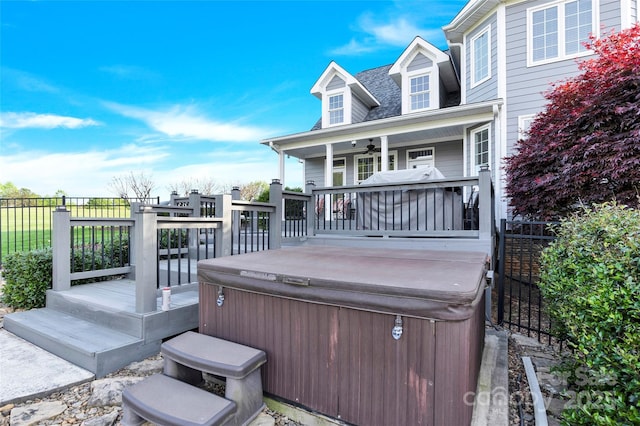 wooden terrace featuring fence, a ceiling fan, and a hot tub