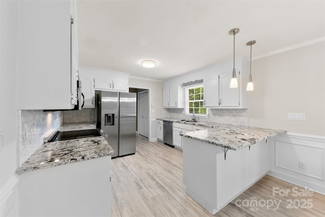kitchen with a sink, a peninsula, crown molding, tasteful backsplash, and appliances with stainless steel finishes