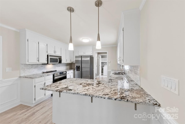 kitchen featuring ornamental molding, a sink, a peninsula, stainless steel appliances, and tasteful backsplash