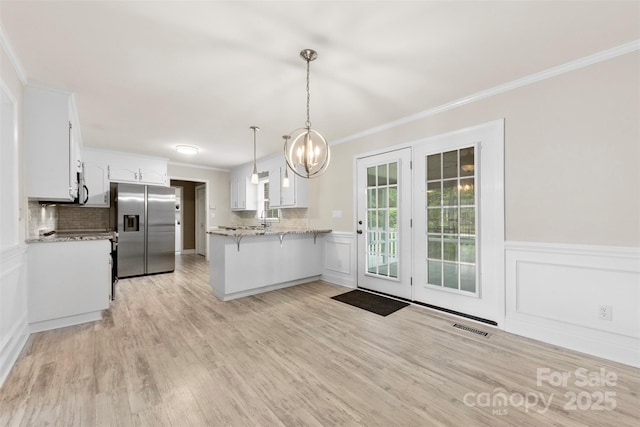 kitchen with crown molding, stainless steel appliances, a peninsula, and white cabinets