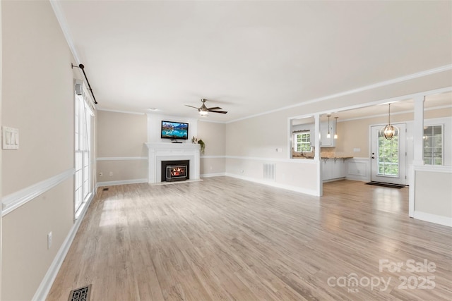 unfurnished living room featuring ceiling fan, ornamental molding, and visible vents