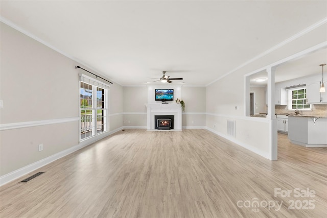 unfurnished living room featuring a fireplace with flush hearth, a ceiling fan, visible vents, and light wood-style floors