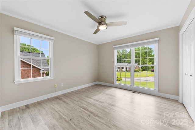 empty room with crown molding, light wood-style flooring, baseboards, and a healthy amount of sunlight