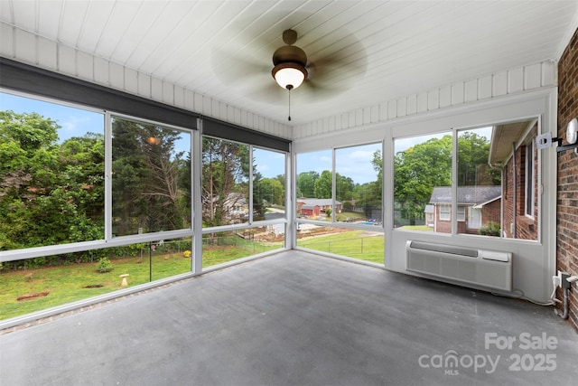 unfurnished sunroom with ceiling fan and a wall mounted AC