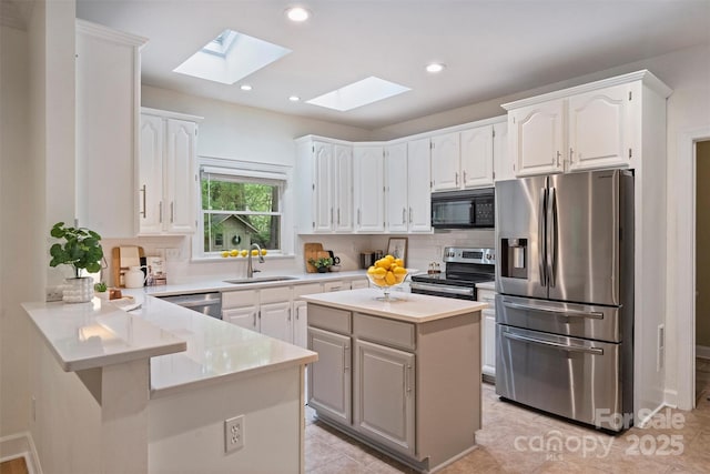 7067 Rocky Falls Rd, Charlotte, NC 28211 - kitchen featuring stainless steel appliances, a skylight, a sink, a peninsula, and decorative backsplash