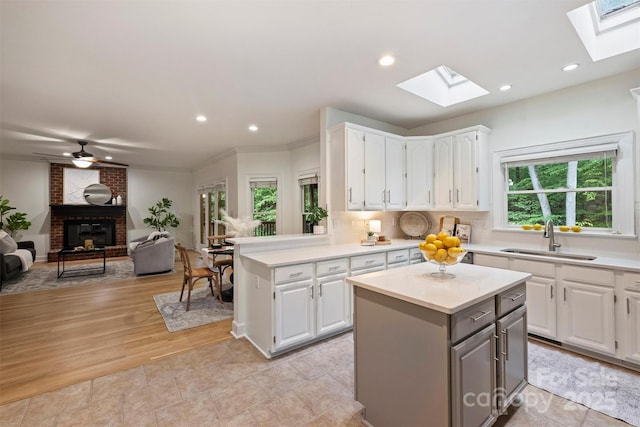 7067 Rocky Falls Rd, Charlotte, NC 28211 - kitchen with a sink, a skylight, a brick fireplace, light countertops, and recessed lighting