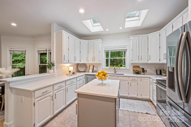 7067 Rocky Falls Rd, Charlotte, NC 28211 - kitchen with appliances with stainless steel finishes, a skylight, tasteful backsplash, light countertops, and a kitchen island