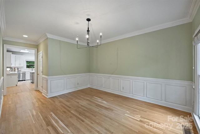 7067 Rocky Falls Rd, Charlotte, NC 28211 - unfurnished dining area with a chandelier, light wood-style flooring, wainscoting, crown molding, and a decorative wall