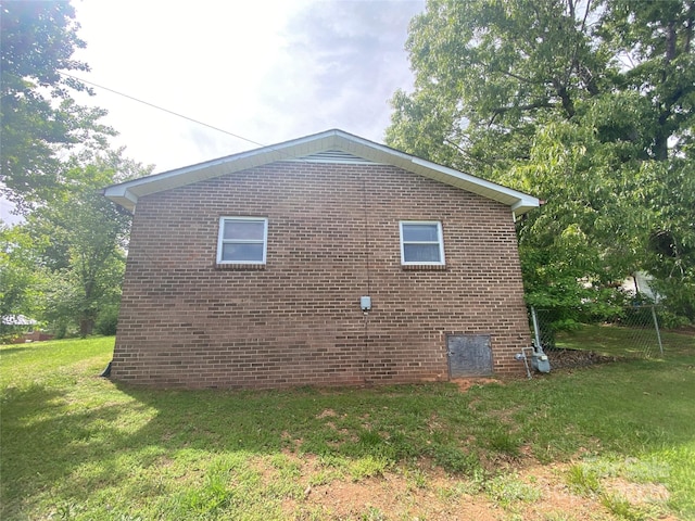 view of side of property with brick siding and a lawn