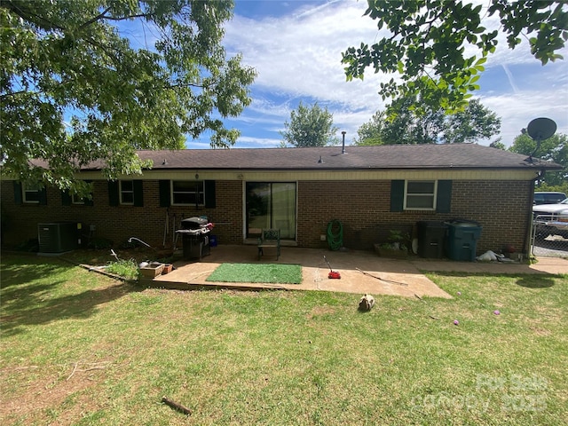 back of property with a lawn, a patio area, central air condition unit, and brick siding