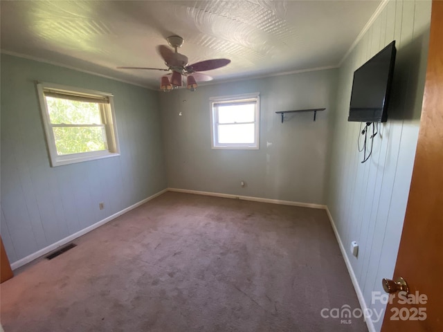 unfurnished bedroom with crown molding, visible vents, ceiling fan, baseboards, and carpet