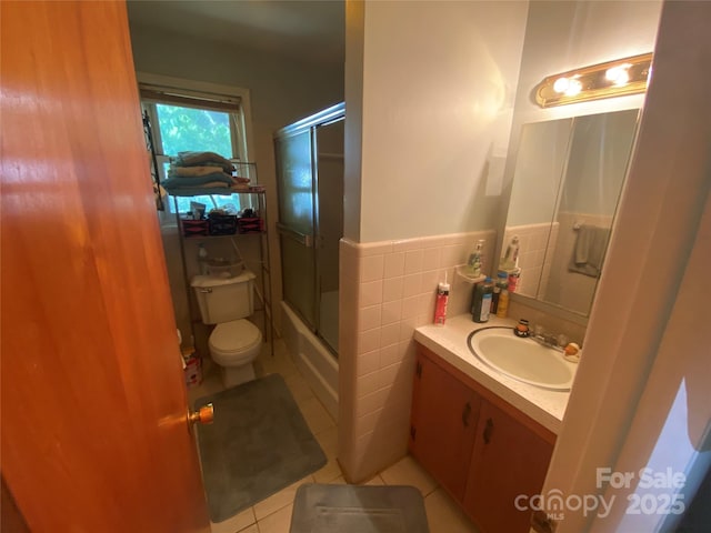 full bath featuring a wainscoted wall, toilet, tile walls, tile patterned floors, and vanity