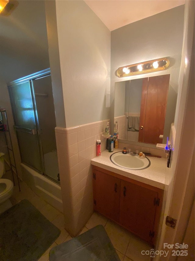 bathroom with tile patterned flooring, wainscoting, a shower stall, toilet, and vanity