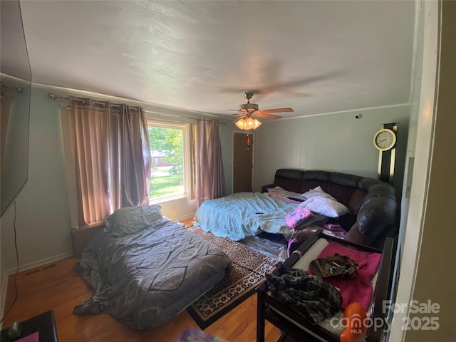 bedroom with wood finished floors, a ceiling fan, and baseboards