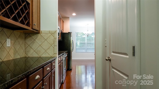 kitchen with stainless steel microwave, baseboards, a chandelier, dark wood-type flooring, and decorative backsplash