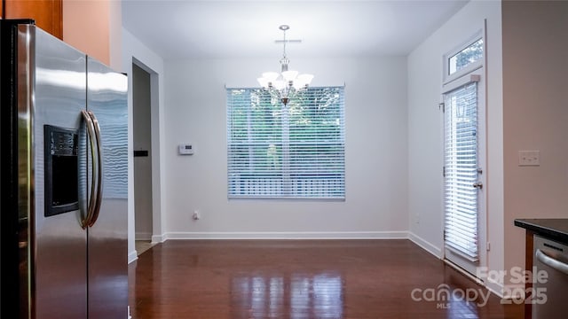 unfurnished dining area with a notable chandelier, dark wood-style flooring, and baseboards