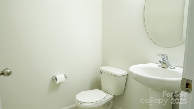 half bathroom featuring toilet and baseboards