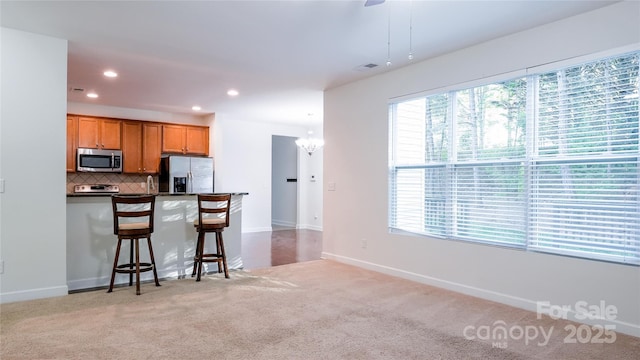 kitchen featuring a kitchen breakfast bar, brown cabinetry, tasteful backsplash, recessed lighting, and appliances with stainless steel finishes