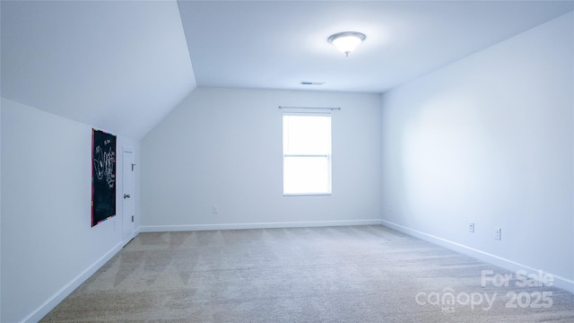 additional living space with visible vents, baseboards, carpet flooring, and vaulted ceiling