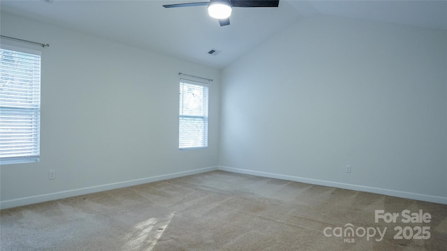 carpeted spare room with visible vents, baseboards, a ceiling fan, and vaulted ceiling