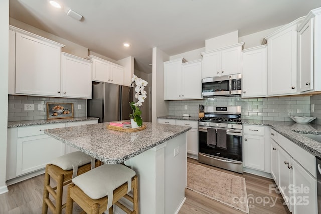 kitchen with a breakfast bar, stainless steel appliances, decorative backsplash, and a kitchen island