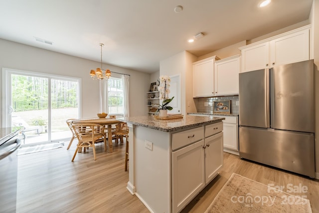kitchen with light wood-style flooring, a center island, an inviting chandelier, visible vents, and stainless steel appliances
