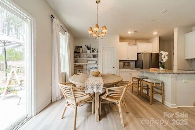 dining area featuring baseboards, a wealth of natural light, a notable chandelier, and light wood-style flooring