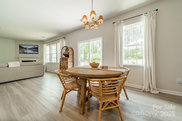 dining room with an inviting chandelier, light wood-style flooring, baseboards, and a healthy amount of sunlight