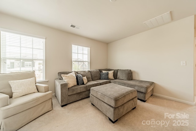 living area featuring plenty of natural light, visible vents, and light carpet