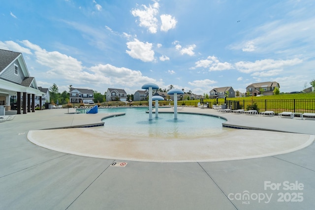 community pool featuring fence, a patio, and a residential view