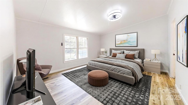 bedroom featuring light wood-style floors, vaulted ceiling, baseboards, and ornamental molding