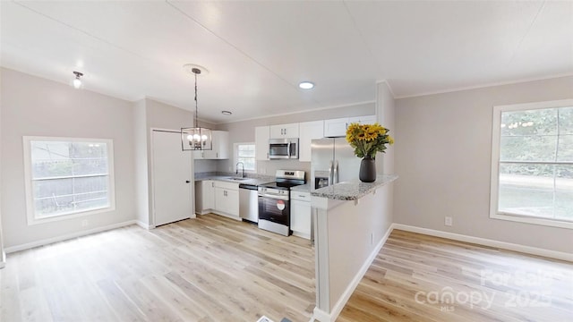 kitchen with a sink, stainless steel appliances, an inviting chandelier, light wood finished floors, and white cabinetry