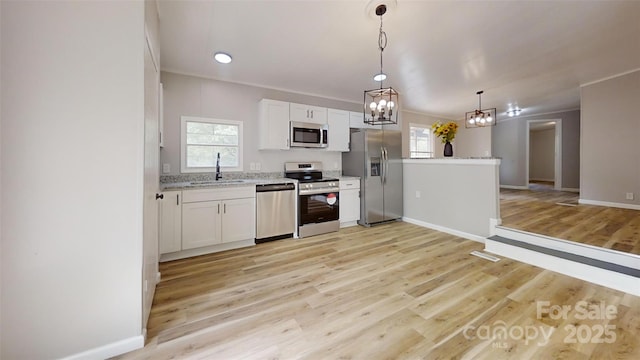 kitchen with a notable chandelier, a sink, light wood-style floors, stainless steel appliances, and white cabinets